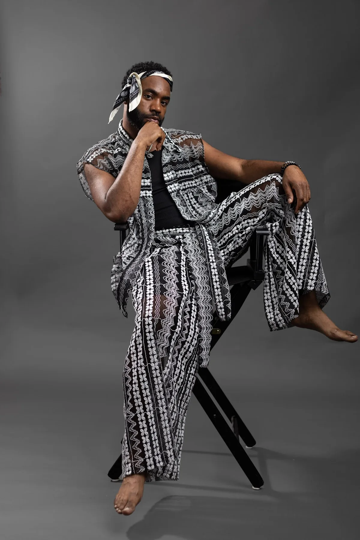 Designer wearing a monochrome patterned two-piece, seated in the studio.