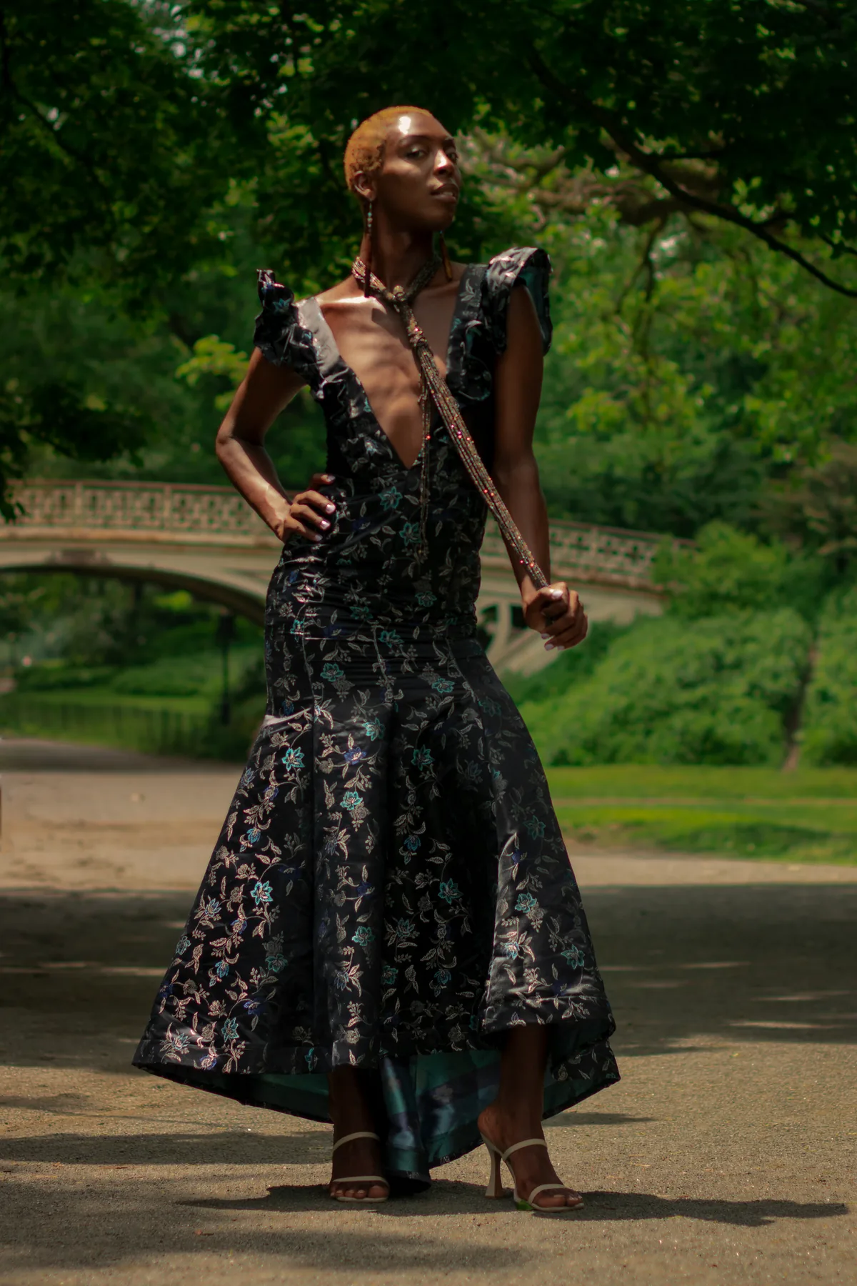 Model in a dark floral gown in a park.